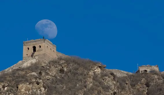 A view of the Great Wall with the moon in the background