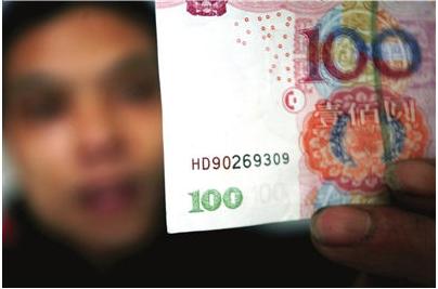 A person checking a Chinese 100 yuan note to see if it's a fake