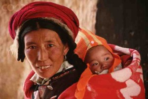 A rural Chinese woman carrying a baby on her back