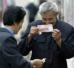 A Chinese man inspecting a Chinese bill to see if it's fake