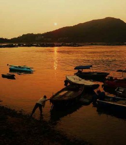 Boats along the shore of the sea during sunset