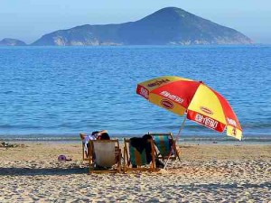 Two people sitting under an umbrella in beach chairs at Shek O Beach