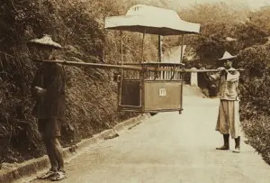 Two Chinese coolies holding an empty sedan chair
