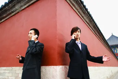 Two Chinese men talking at a wall