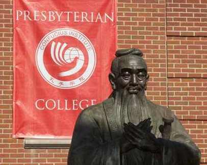 A statue of Confucius in front of a university banner