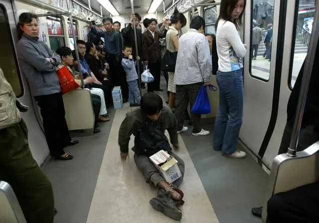 A homeless Chinese man sitting on the floor of a subway 
