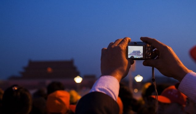 A tourist taking a photo of the Forbidden city with their camera