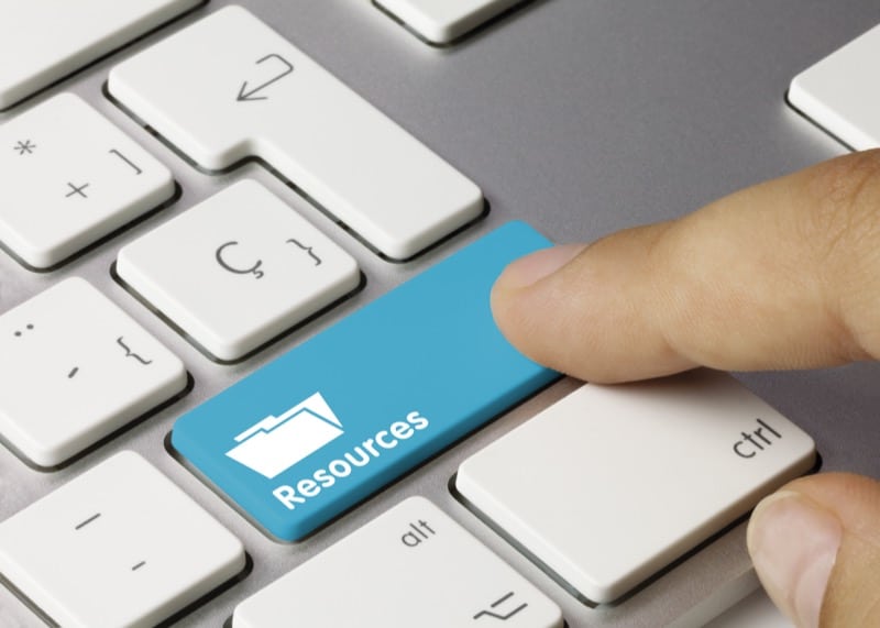 Finger pushing a key titled "Resources" on a computer keyboard